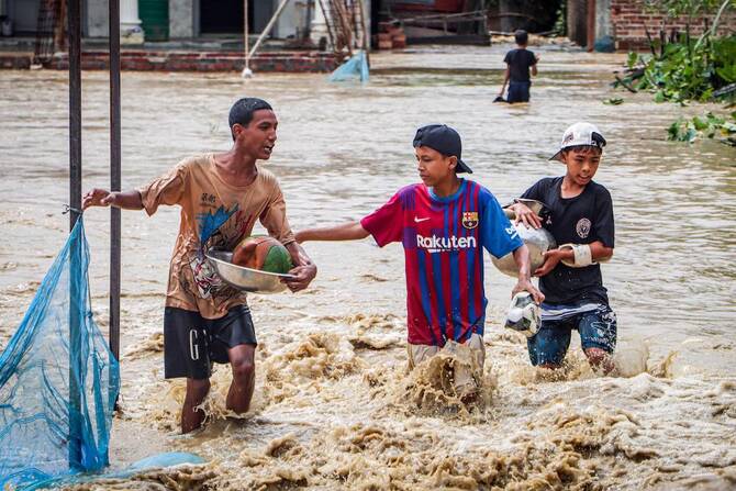 Above, youngsters wade through a flooded street after heavy monsoon rain showers in India on Sept. 15, 2025. (AFP)