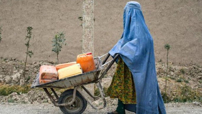 An Afghan burqa-clad woman pushes a wheelbarrow loaded with empty water canisters as she walks along a street in the Koshkak area of the Balkh province on October 5, 2025. Photo: AFP via BSS.