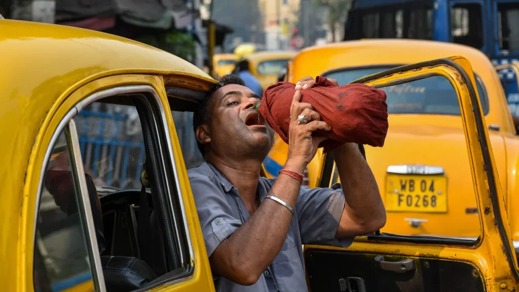 A taxi driver is seen drinking water from a bottle during afternoon heat in Kolkata, India.
