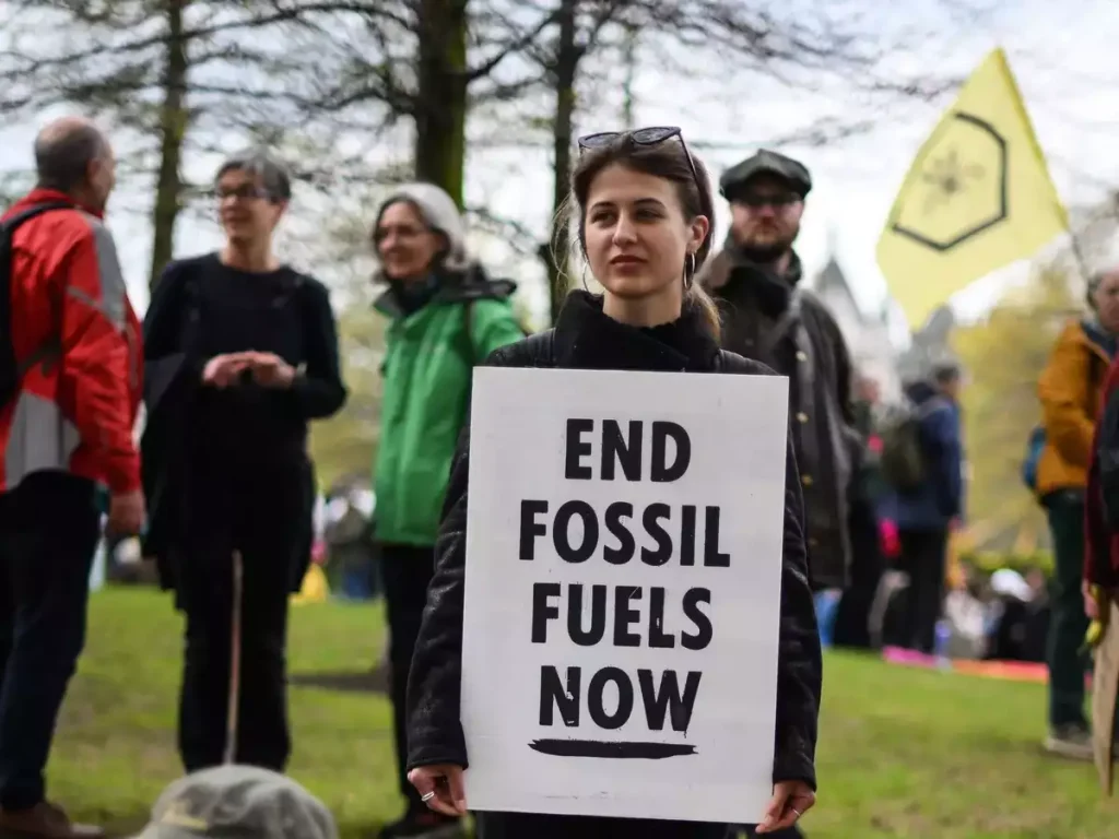 A protester holds a placard reading "End Fossil Fuels now" during a demonstration march to end fossil fuels in central London, on April 24, 2023