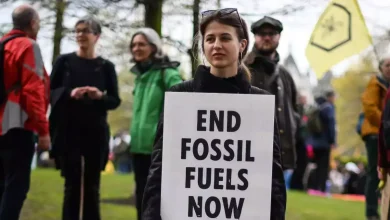A protester holds a placard reading "End Fossil Fuels now" during a demonstration march to end fossil fuels in central London, on April 24, 2023