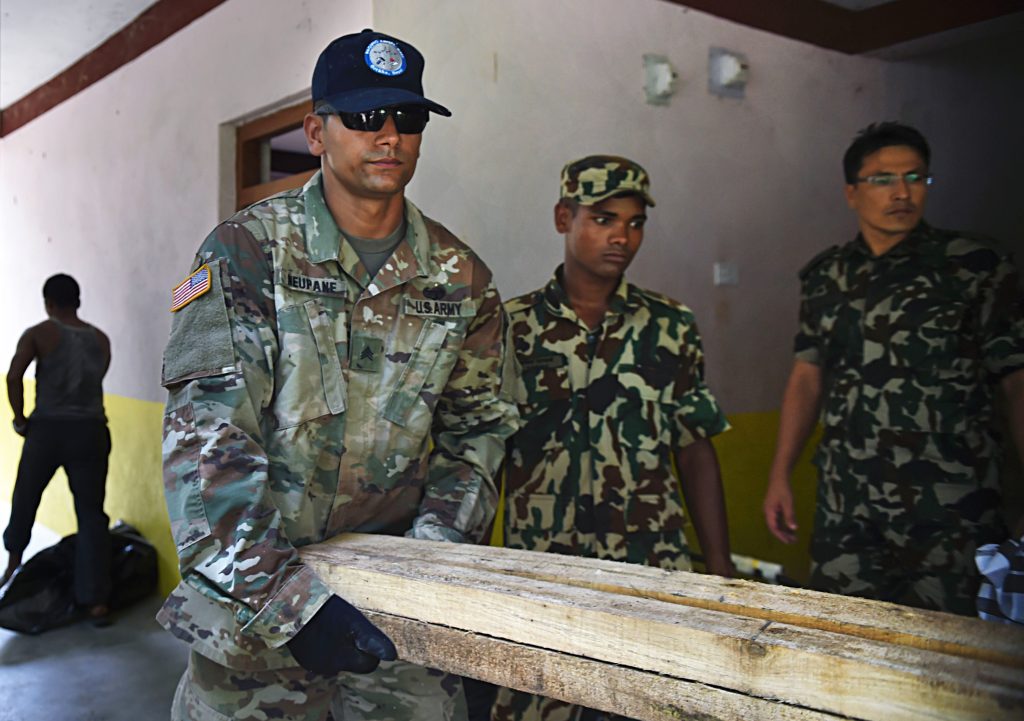 U.S. Army Sgt. Rajeev Neupane, 523rd Engineer Support Company, 130th Engineer Brigade interior electrician, carries lumber supplies at the Shree Mahendra Higher Secondary School during Pacific Angel (PACANGEL) 17-4 in Gorkha, Nepal.