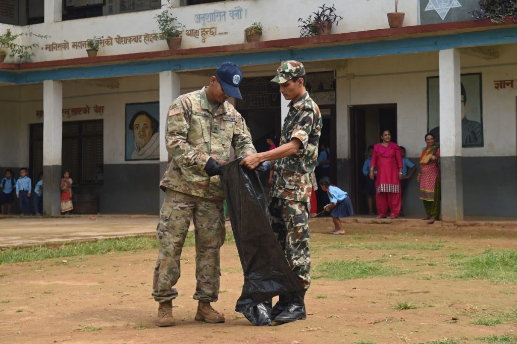 U.S. Army Sgt. Rajeev Neupane, 523rd Engineer Support Company, 130th Engineer Brigade interior electrician, and a Nepal army counterpart pick up debris near an engineering site at the Shree Mahendra Higher Secondary School during Pacific Angel