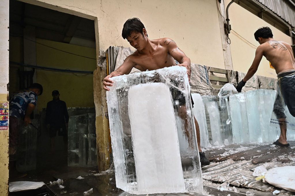 Workers move blocks of ice into a storage unit at a fresh market during heat wave conditions in Bangkok on April 25.