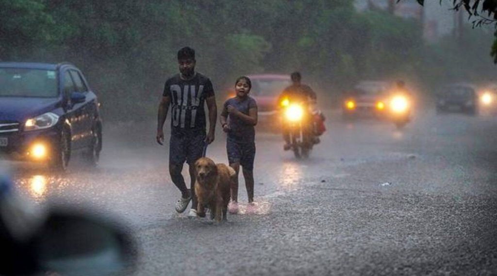 A man along with his pet walks down a waterlogged load as people commute amid monsoon rains, in New Delhi, Thursday, July 6, 2023.