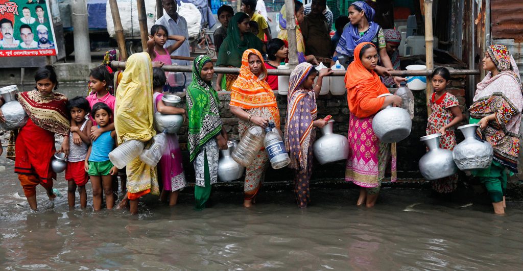 Women and children collect drinking water from a water logged area in Dhaka, Bangladesh. Credit: Mehedi Hasan/Alamy Stock Photo.