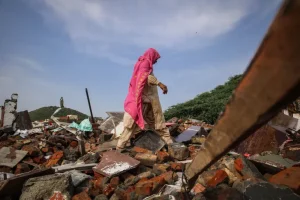 A woman walks amid the debris of her son’s demolished shop in Nallhar, Nuh [Md Meharban/Al Jazeera]