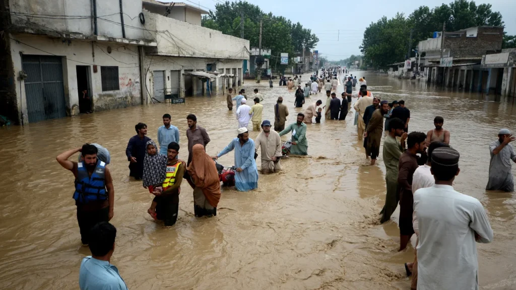 Displaced people wade through a flooded area in Peshawar, Khyber Pakhtunkhwa, Pakistan on August 28, 2022.