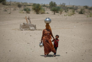 A woman walks back towards her home after filling water from a shallow well in a desert area on a hot summer day in Barmer, Rajasthan, India, April 26, 2024.  REUTERS