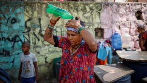 A woman pours water on her head after filling her containers with drinking water from a municipal tanker on a hot summer day in New Delhi, India, May 21, 2024. REUTERS