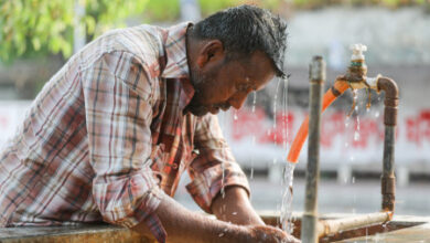 A man splashing his face with water during intense Summer heat. File Photo