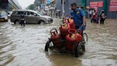 A worker transports cylinders through waterlogged streets during heavy rains in Mumbai, India. (AP)