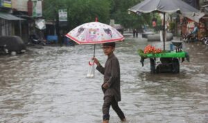 A Child holds an umbrella as he wades through a flooded street after a downpour in Lahore, Pakistan July 9, 2025. (REUTERS)