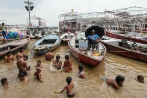 A member of the Jal Police Department, a wing of the police force responsible for maintaining law and order around the water bodies, keeps watch from a boat as people take baths in the flooded Dashashwamedh Ghat after heavy monsoon rains induced a rise in the water level of the river Ganges in Varanasi on August 11, 2025. (AFP)