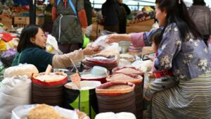 In this photograph taken on January 10, 2024, a woman carrying a child buys grains from a stall at a market in Bhutan's capital Thimphu. PHOTO: AFP