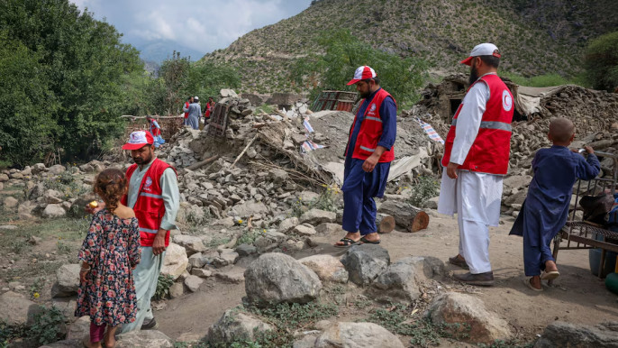 Red Crescent volunteers walk next to damaged houses as they reach Lulam village to help the victims following a deadly magnitude-6 earthquake that struck Afghanistan on Sunday, in Nurgal district, Kunar province, Afghanistan, September 3, 2025. REUTERS/Sayed Hassib