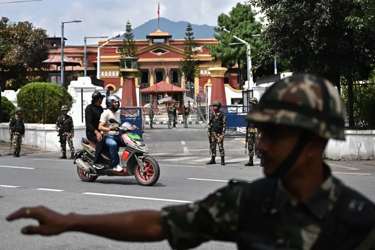 Motorcyclists ride past army personnel guarding Nepal's presidential palace outside of a curfew imposed to restore law and order in Kathmandu, on September 12, 2025 [Pedro Pardo/AFP]